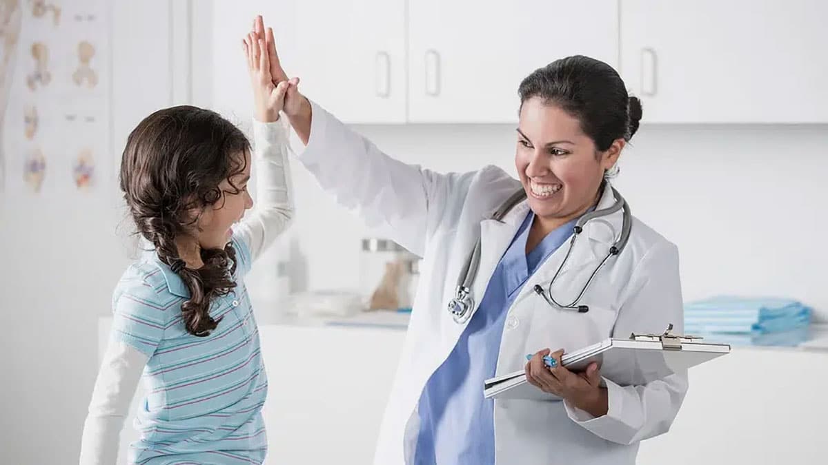Doctor high-fiving a young patient, symbolizing positive medical UX design and patient-centered healthcare solutions.