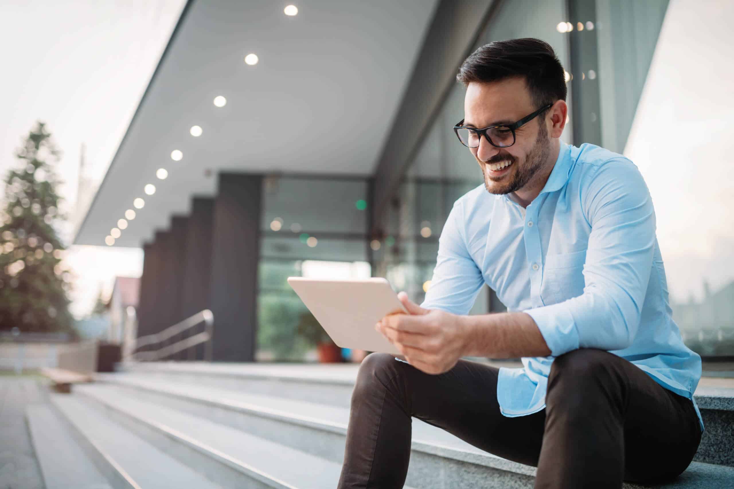 Man smiling while looking at a tablet